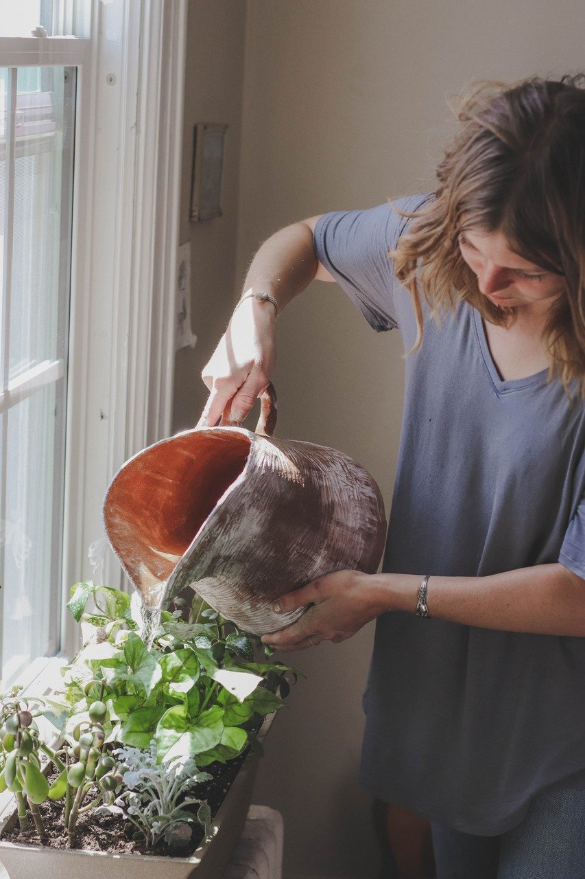 a woman watering her flowers on the window