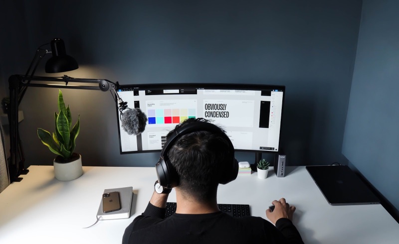 Person mit Kopfhörern, die Grafikdesign auf ihrem Desktop macht