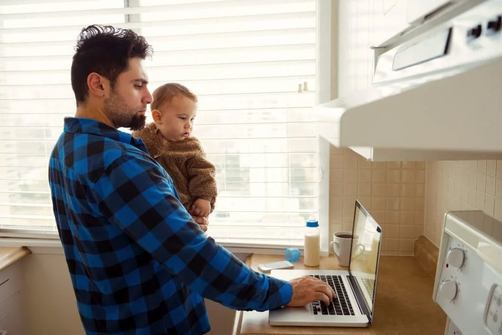 homem segurando uma criança olhando para o computador