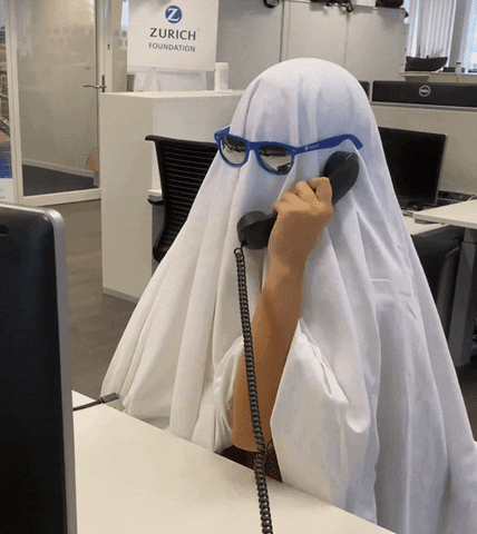 A person in a poorly made ghost costume with glasses is on the phone talking.