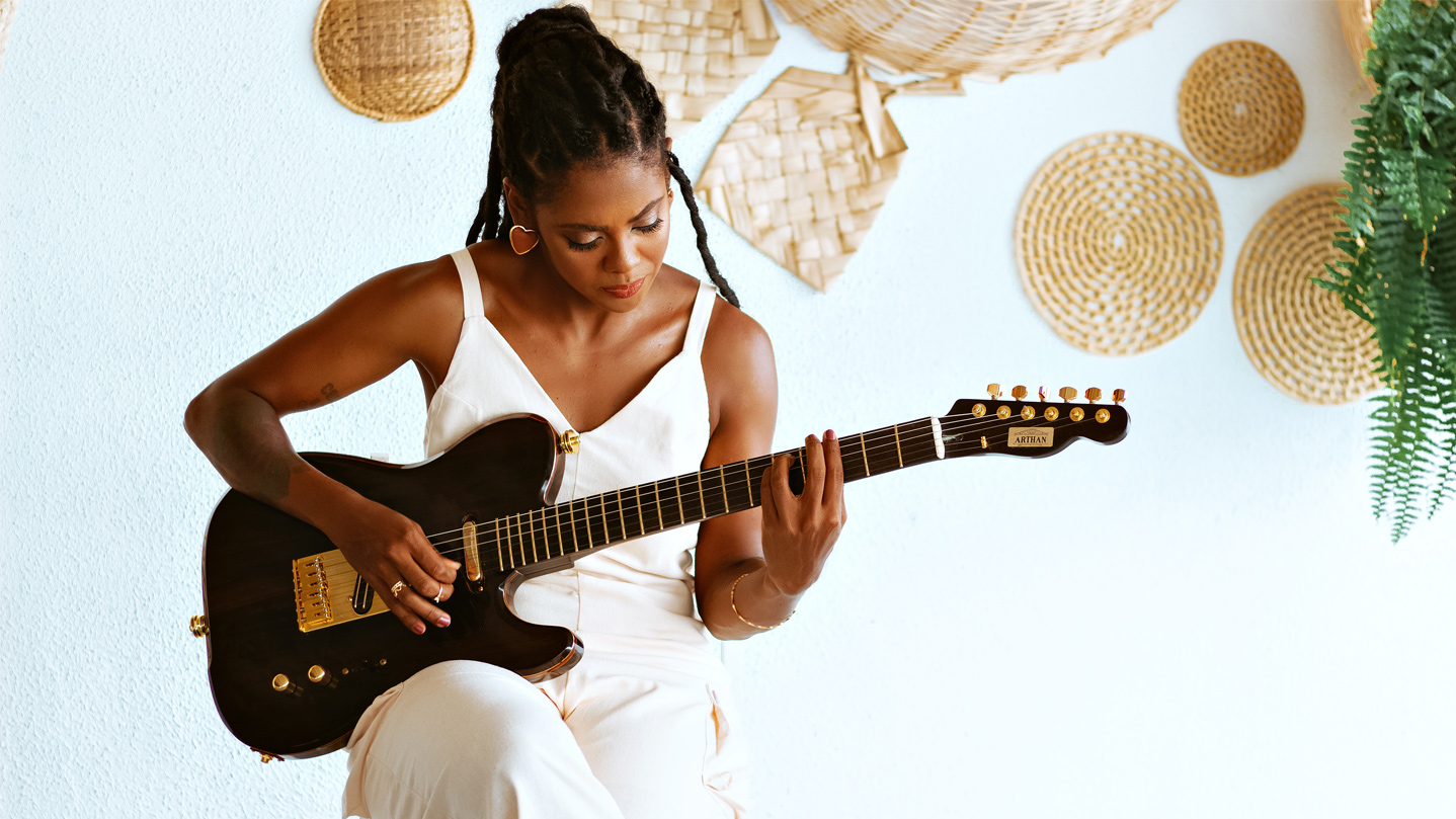 Sitzende Frau, die eine E-Gitarre spielt.