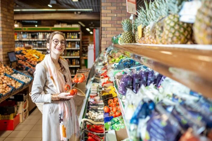 uma mulher escolhendo vegetais em uma loja de produtos naturais.