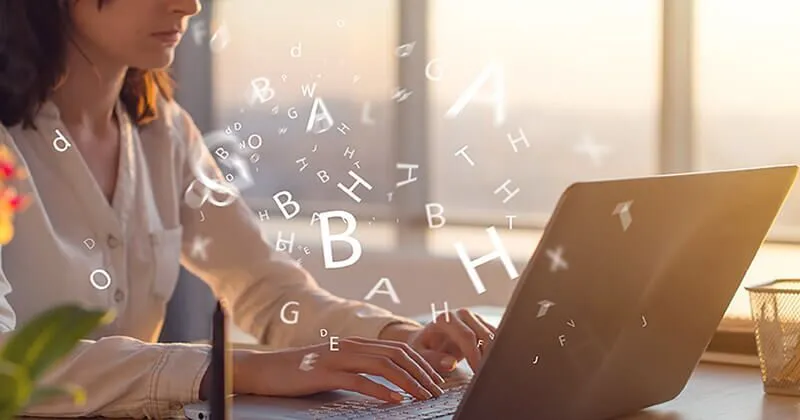 Une femme tape une copie sur un ordinateur portable, diverses lettres de l'alphabet flottent autour d'elle.