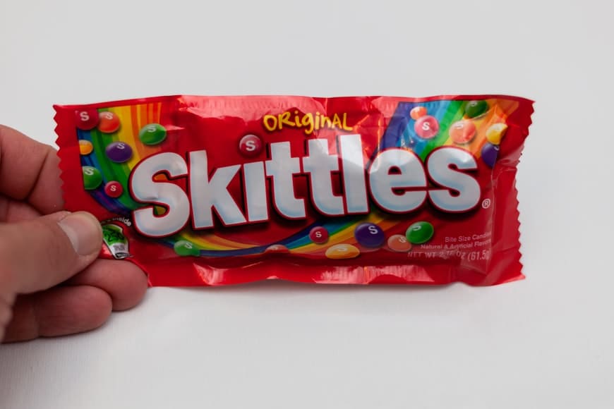 orang yang memegang paket skittles merah