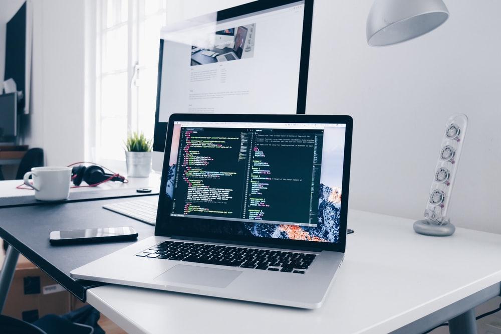 忙碌的办公桌上的 MacBook，屏幕上有几行代码